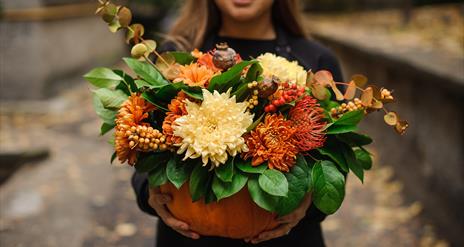 A pumpkin filled with autumnal flowers