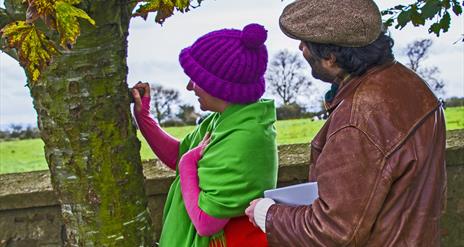 Brightly dressed lady and gentleman looking at tree