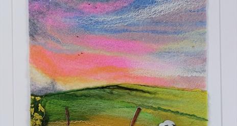 felt image of a colourful sky, fields ands sheep
