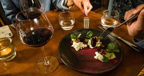 A plate of food and glass of red wine