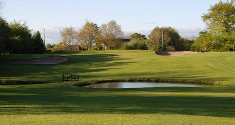 image of the gold course with sand bunker and small lake