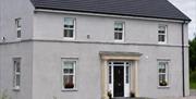 Carland Cottage exterior with gravel driveway and surrounding greenery.