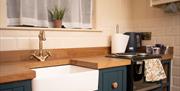 Fairy Tree Lodges Kitchen area with work top, low level cupboards and Belfast Sink, hob and oven.