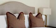 Double Bed with cushioned headboard and patterned cushions.