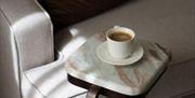 Armchair with marble side table and cup of coffee.