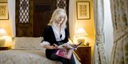 Woman reading magazine while sitting on bed