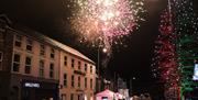 Multi-coloured fireworks are exploding in the sky over the roof of buildings on Magherafelt's Main Street