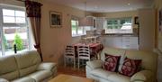 Open plan kitchen, dining and living area with 2 cream 2 seater sofas and dining table with 4 chairs