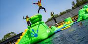 People jumping off the inflatable waterpark into the water