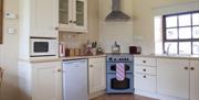 Kitchen area with corner cooker, sink and window