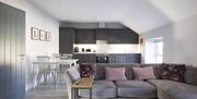 open plan kitchen, dining and living area with table and 4 chairs and grey corner sofa
