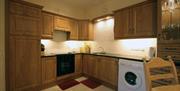 A wooden kitchen with a washing machine