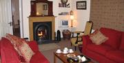 Living room with two red sofas, an arm chair, fireplace and coffee table