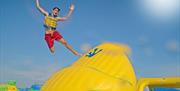 Boy jumping off a large inflatable into water