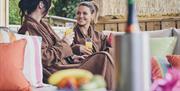 Two women in robes enjoying a glass of orange