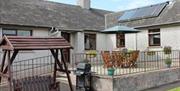 Outside image of house with accessibility ramp, table and chairs, wooden swing chair