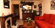 Living room with an orange sofa, mahogany dresser, fireplace and shelves filled with books