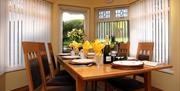 Dining table and six chairs in a room with windows on each side