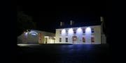 Image of a large two story building lit with four flood lights