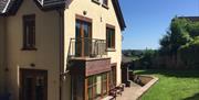 Outside of 2 storey yellow house showing patio doors to small balcony