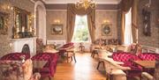 Plush velvet seating and tables with large fireplace and hold lightings with long drapes