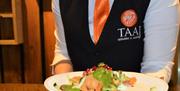 A waiter in the Taaj restaurant holding a plate of Indian food