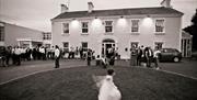 Black and white image of a wedding party gathered outside