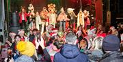 Members of the Craic Theatre are on stage dressed in panto costumes with crowds of people watching in the foreground of the picture