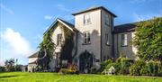 External view of Corick House with ivy climbing the external walls and surrounded by landscaped gardens