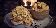 A plate of food in front of an open fire on a restaurant table