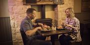 A couple having a meal in front of a stove fire