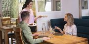 A couple sitting at a table being served a meal at a restaurant