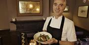 Chef holding a plate of food in front of an open fire