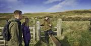 A couple at a gate with a tour guide in the Sperrin Mountains