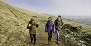 A couple with a tour guide on a walk in the Sperrin Mountains