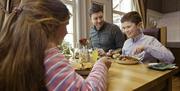 A little boy smiling with his family having a meal in a restaurant