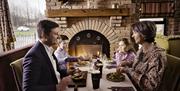 A family having a meal in a restaurant in front of an open fire