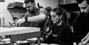 Black and white image of staff in a kitchen plating up food