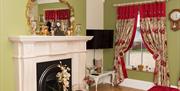 Room with green walls, a fireplace and floral curtains