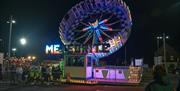 Large circular spinning amusement ride lit up with coloured lights
