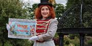 Girl dressed as circus master holding poster of the event
