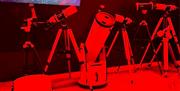 7 telescopes on tripods in front of screed mounted on wall