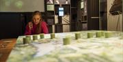 A lady listens to an audio device whilst looking at a display at Seamus Heaney HomePlace