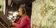 A lady listens to an interactive display at the Heaney Homeplace