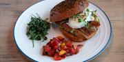 A plate of poached egg on sausage in a bagel