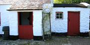 Entrance to the white washed stone cottage with a red half door, closed at the bottom and opened in the top half.