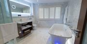 tiled bathroom with bath, floor lighting, hanging robes, shower, sink and toilet