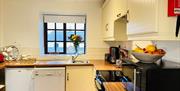 Bright fitted kitchen with modern appliances and window view.