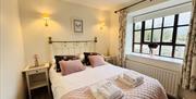 Double bedroom with pink accents and large window.