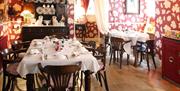 Dining room with patterned red wallpaper and mahogany furniture